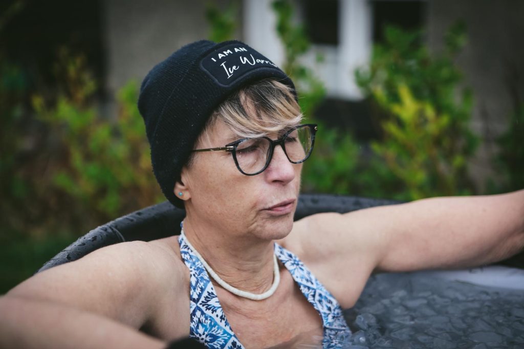 woman sat in ice bath outside with eyes closed as she breathes out clearly