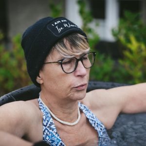 woman sat in ice bath outside with eyes closed as she breathes out clearly